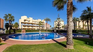 Un hotel con piscina, palme e un cielo azzurro limpido.