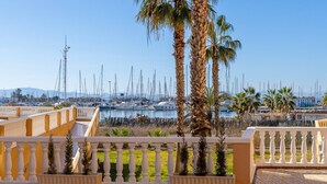 Una marina con barche, palme e un balcone con fioriere.
