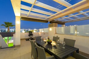 An outdoor dining area with a table set for four, surrounded by wicker chairs, under a glass ceiling structure. - Laguna Dream by Fidalsa (Guardamar del Segura)