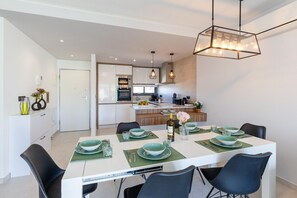 A modern dining area with a white table set for four, surrounded by black chairs. - Laguna Dream by Fidalsa (Guardamar del Segura)