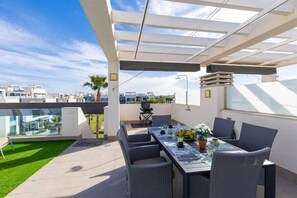 A rooftop patio with a table set for dining, outdoor furniture, and a view of the cityscape. - Laguna Dream by Fidalsa (Guardamar del Segura)
