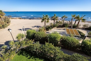 A beach view with palm trees, a sandy area, and a clear blue sky. - Fidalsa Utopia Junto al mar (Torrevieja)