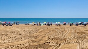 A sandy beach with footprints and people under umbrellas. - Ocean Blue Eyes by Fidalsa (Guardamar del Segura)