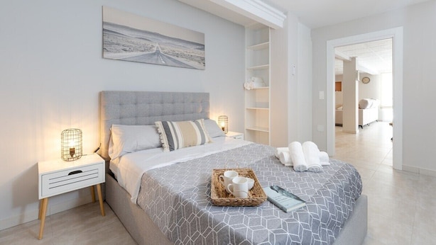 A bedroom with a bed, bedside tables, a nightstand, a tray with cups and a book, and a painting on the wall. - Ocean Blue Eyes by Fidalsa (Guardamar del Segura)