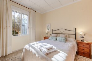 Ein Schlafzimmer mit einem Bett, zwei Nachttischen, einem Fenster mit Vorhängen und einem Wandbild.