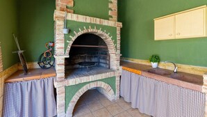 Un four en briques, une nappe à carreaux, un petit évier et une plante en pot.