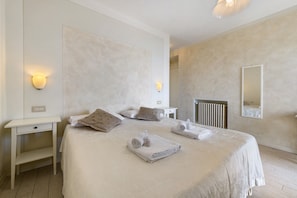 A bedroom with a large bed, bedside tables, a mirror, and a radiator.