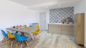 A modern kitchen with a tiled backsplash, a dining area with a table and chairs, and a door leading to another room. - Beautiful Bay Views by Fidalsa (Finestrat)