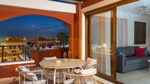 A balcony with a table and chairs, a sofa, and a view of a cityscape at dusk. - Beautiful Bay Views by Fidalsa (Finestrat)