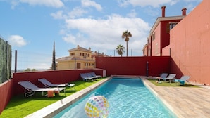 A swimming pool with lounge chairs, a palm tree, and a building in the background. - Beautiful Bay Views by Fidalsa (Finestrat)