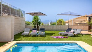A swimming pool with lounge chairs and umbrellas, surrounded by a fenced area with a view of the city. - Mountain Beautiful by Fidalsa (Busot)