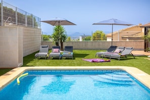 A swimming pool with lounge chairs and umbrellas, surrounded by a fenced area with a view of the city. - Mountain Beautiful by Fidalsa (Busot)
