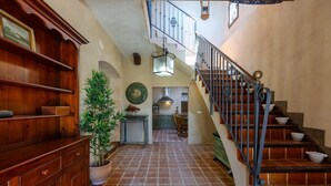 A wooden staircase with a metal railing, a potted plant, and a kitchen area in the background. - Historical Palms by Fidalsa (Elche)
