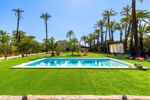 A rectangular swimming pool surrounded by well-maintained grass, palm trees, and outdoor furniture. - Historical Palms by Fidalsa (Elche)