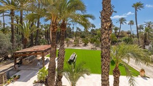 A patio area with a pergola, a green lawn, and tall palm trees. - Historical Palms by Fidalsa (Elche)