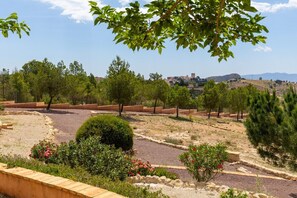 Ein angelegter Garten mit Wegen, Bäumen und Blick auf eine entfernte Stadt.