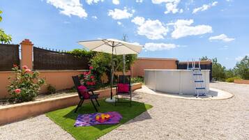An outdoor patio with a pool table, chairs, and a table with food.