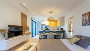 A modern living room with a sofa, TV, and dining area. - Dreamscape Villa by Fidalsa (Los Alcazares)