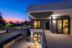 A modern building with a balcony, a dining area, and a bedroom visible through glass doors. - Dreamscape Villa by Fidalsa (Los Alcazares)