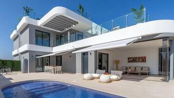 A modern two-story house with a swimming pool, outdoor seating, and a balcony.