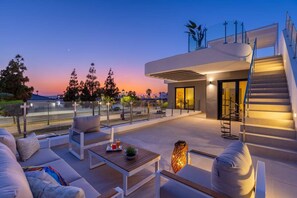 A modern outdoor living area with a sofa, table, and staircase. - Dreamscape Villa by Fidalsa (Los Alcazares)