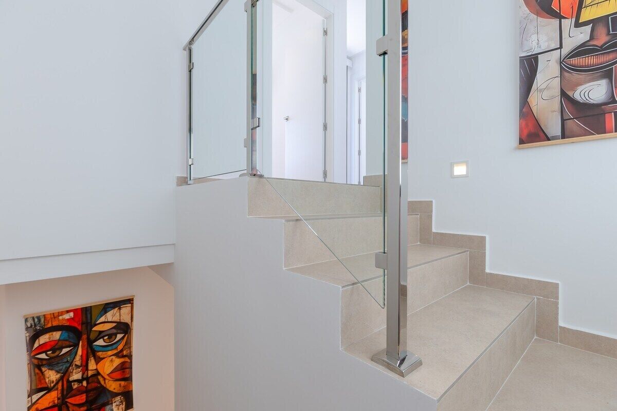A modern staircase with glass railings and beige steps.