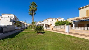 Una calle residencial con casas, una palmera y un césped bien cuidado.