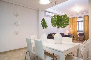 A modern dining area with a white table, chairs, and large decorative vases.