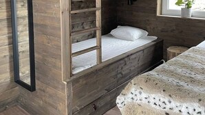 Ein Stockbett mit einer Leiter, ein Fenster mit Blick und eine Deckenleuchte.
