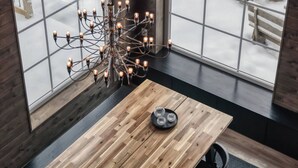 Ein Zimmer mit einem großen Fenster, einem Holztisch und einer Chandelüster.