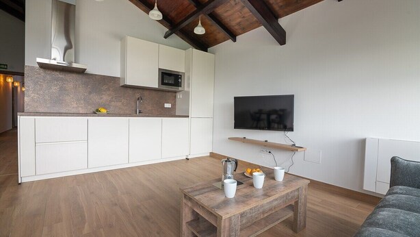 Una cocina moderna con armarios blancos, un microondas y un televisor montado en la pared.