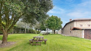 Un espacio al aire libre con césped, mesas de picnic y un edificio de piedra.