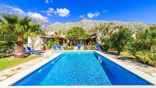 A swimming pool with lounge chairs, a mountain backdrop, and a building with a traditional architectural style. - Villa 'Martorell' with Private Pool, Wi-Fi and Air Conditioning (Illes Balears)