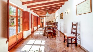 A hallway with wooden beams, a dining table with chairs, and a chandelier. - Villa 'Martorell' with Private Pool, Wi-Fi and Air Conditioning (Illes Balears)