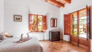 A bedroom with a bed, a dresser, a window with shutters, and a radiator. - Villa 'Martorell' with Private Pool, Wi-Fi and Air Conditioning (Illes Balears)