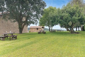A grassy outdoor area with picnic tables and a stone building. - Infinity Coast I by Fidalsa (Miengo)