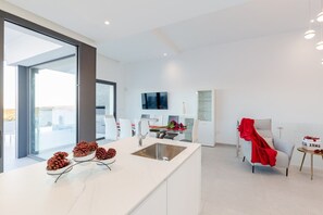 A modern kitchen with a large island, a dining area, and a living space with a TV. - Fidalsa 5 Stars Sea Views (Rojales)