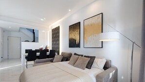 Ett modernt hotellrum med en stor säng, ett skrivbord och en stol, en trappa och konstverk på väggarna.