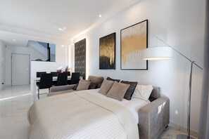 A modern hotel room with a large bed, a desk, and a chair, a staircase, and artwork on the walls. - Laguna Rocher by Fidalsa (Guardamar del Segura)