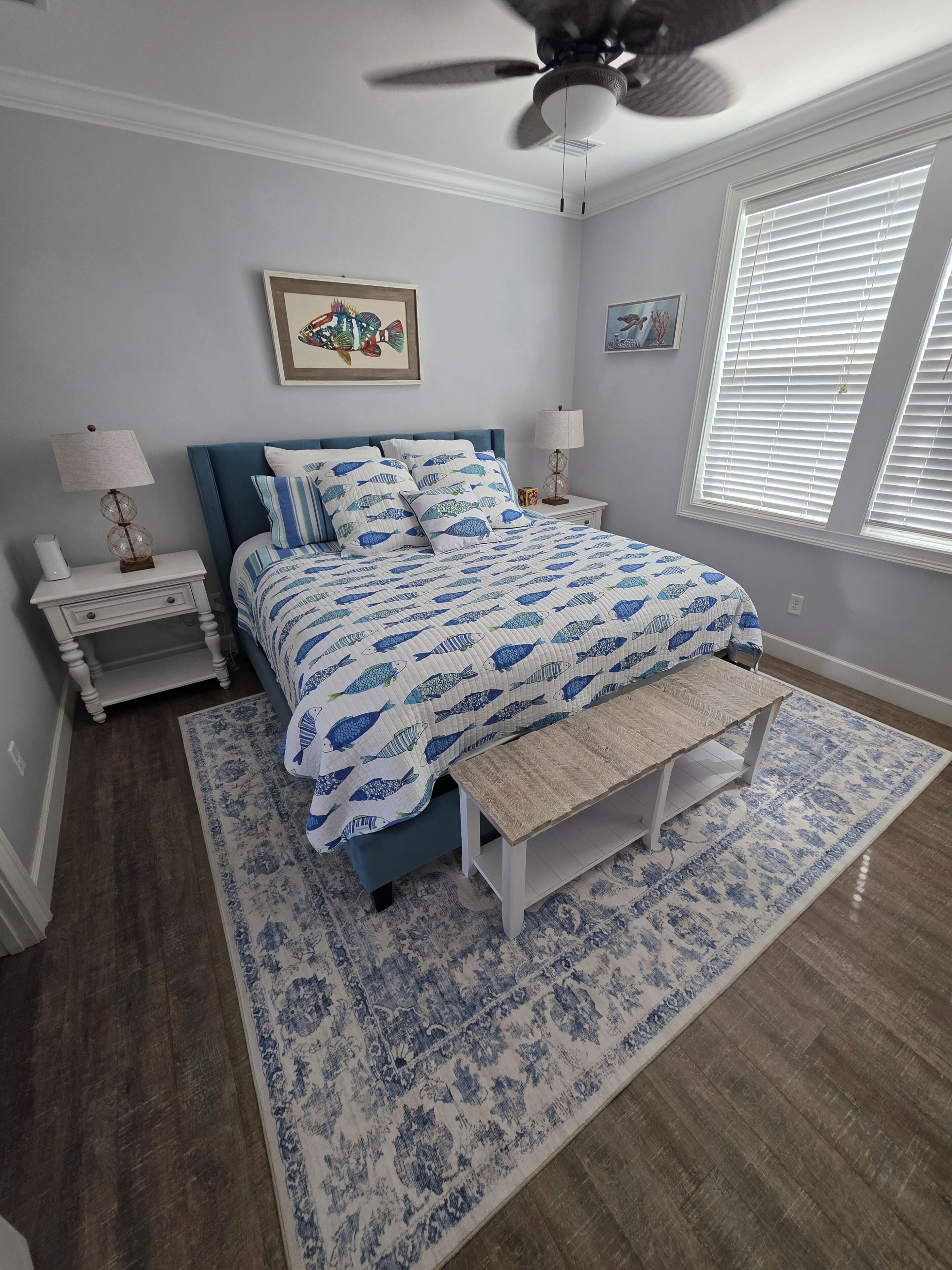 A bedroom with a bed, bedside tables, a ceiling fan, and a window with blinds.