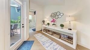 A hallway with a white console table, two wall-mounted lamps, a decorative mirror, and wicker baskets. - Pineapple Paradise-Pool Home 2Blocks to the Beach-By Island Real Estate (Holmes Beach)