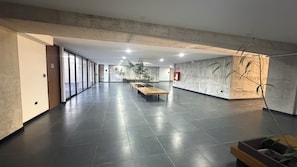 A spacious lobby with a long reception desk, potted plants, and a fire extinguisher on the wall. - Cozy studio with AC in a superb San Salvador location (San Salvador)