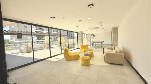 A spacious room with large windows, a ping pong table, and yellow bean bag chairs. - Cozy studio with AC in a superb San Salvador location (San Salvador)