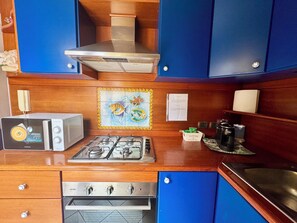 A compact kitchen with a microwave, gas stove, oven, and blue cabinets. - Akragas home 2 with city view (Agrigento)