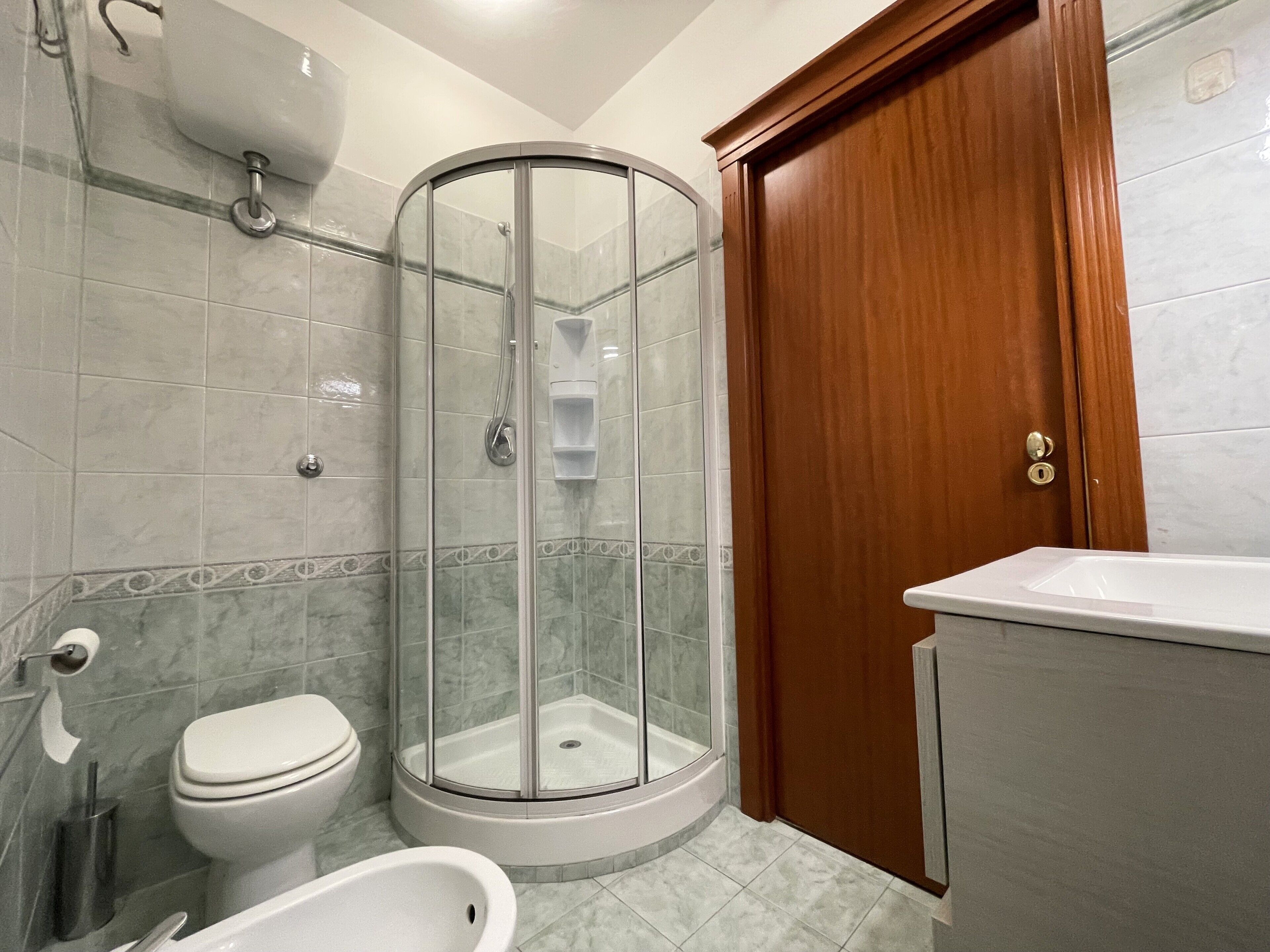 A bathroom with a glass shower enclosure, a toilet, a bidet, and a sink.