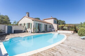 Una casa con piscina, patio y jardín.