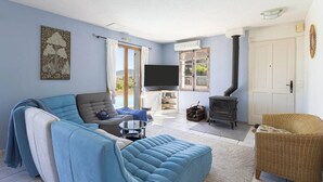 Una sala de estar con sofá, televisión y chimenea.
