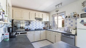 Una cocina con armarios blancos, estufa, lavavajillas y ventana.