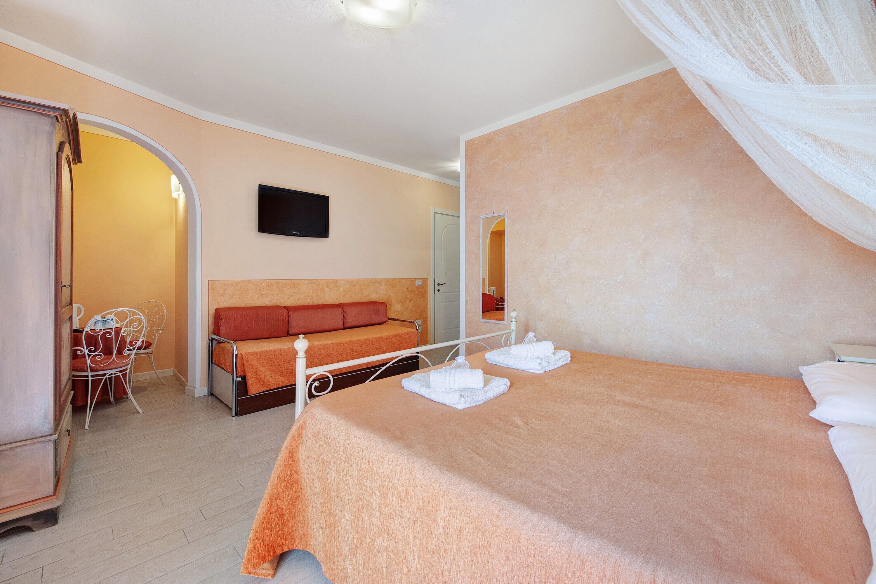 Une chambre à coucher avec un lit, un canapé, une télévision et un miroir.