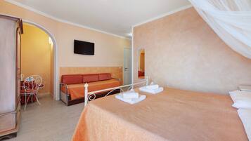 Une chambre à coucher avec un lit, un canapé, une télévision et un miroir.